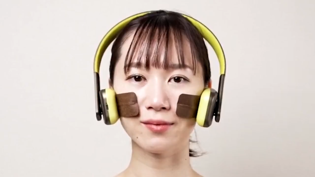 ヘッドフォンのような形のFACE PLAYER IIを装着し、パッドを頬に当てているところ